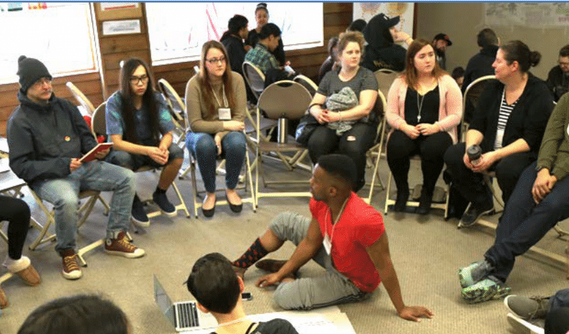 a group of people sitting in a circle, possibly in a discussion or workshop setting